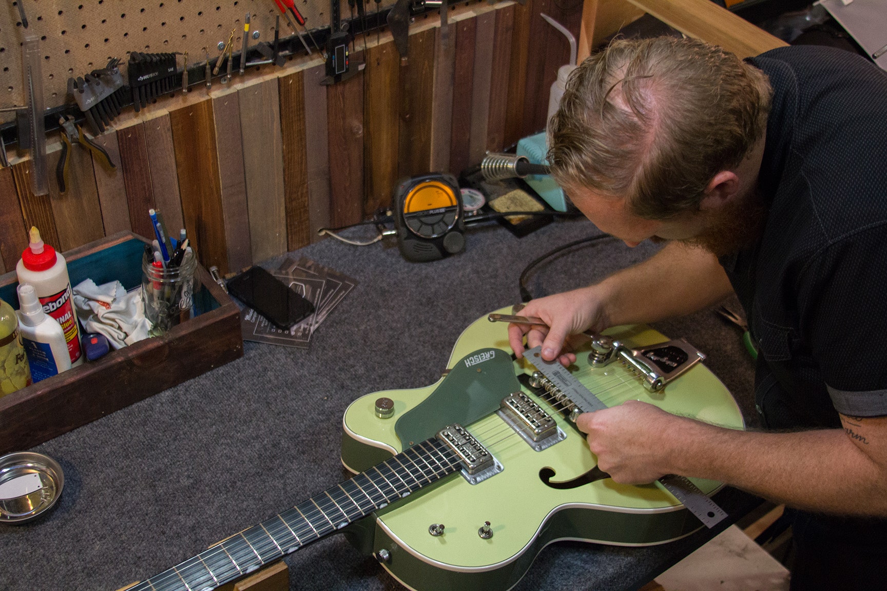 A person who is working carefully on mending the guitar